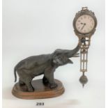 Figural swinging clock with a patinated elephant holding a brass swinging pendulum clock 10” high (