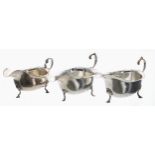 Three similar silver sauce boats, each with card cut flared rims and C-scroll handles, raised on