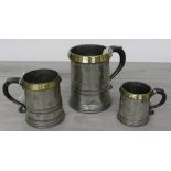 Three early 19th century pewter tankards to include a quart, pint and half pint, each with brass