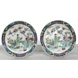 Pair of Chinese porcelain plates, decorated with figures in a garden with a blossom tree, within a