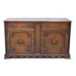 Oak sideboard, the moulded top over two short drawers and two panelled cupboard doors with carved