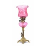 Victorian brass and cranberry glass oil lamp, with fluted flared shade and glass font raised on a