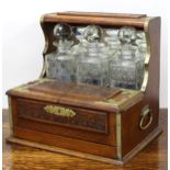 Early 20th century carved oak tantalus, for three decanters, with a front section having a hinged
