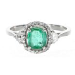 Attractive modern 18ct white gold oval emerald and diamond cluster ring with diamond shoulders,