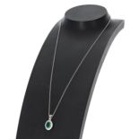 Modern 18ct white gold pendant set with an oval emerald and halo of round brilliant cut diamonds, on