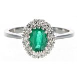 Modern 18ct white gold oval emerald and diamond cluster ring, the emerald 0.70ct approx, the
