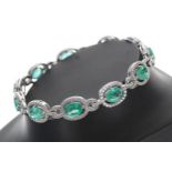 Modern attractive 18ct white gold emerald and diamond line bracelet, oval emeralds 7.12ct total,