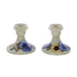 Pair of Moorcroft Pottery 'Pansy' squat candlesticks, bearing Late Queen Mary labels to the base,