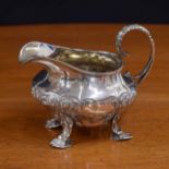 George IV silver cream jug, repousse decorated with flowers and C scrolls, with a leaf capped handle