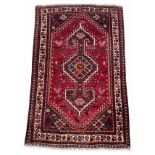 Iranian handmade Shiraz rug, labelled, on a dark red ground, 70" x 44" approx