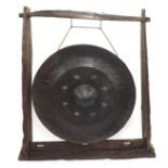 Very large circular iron gong with decorative embossed centre, 43" diameter, suspended in a wooden
