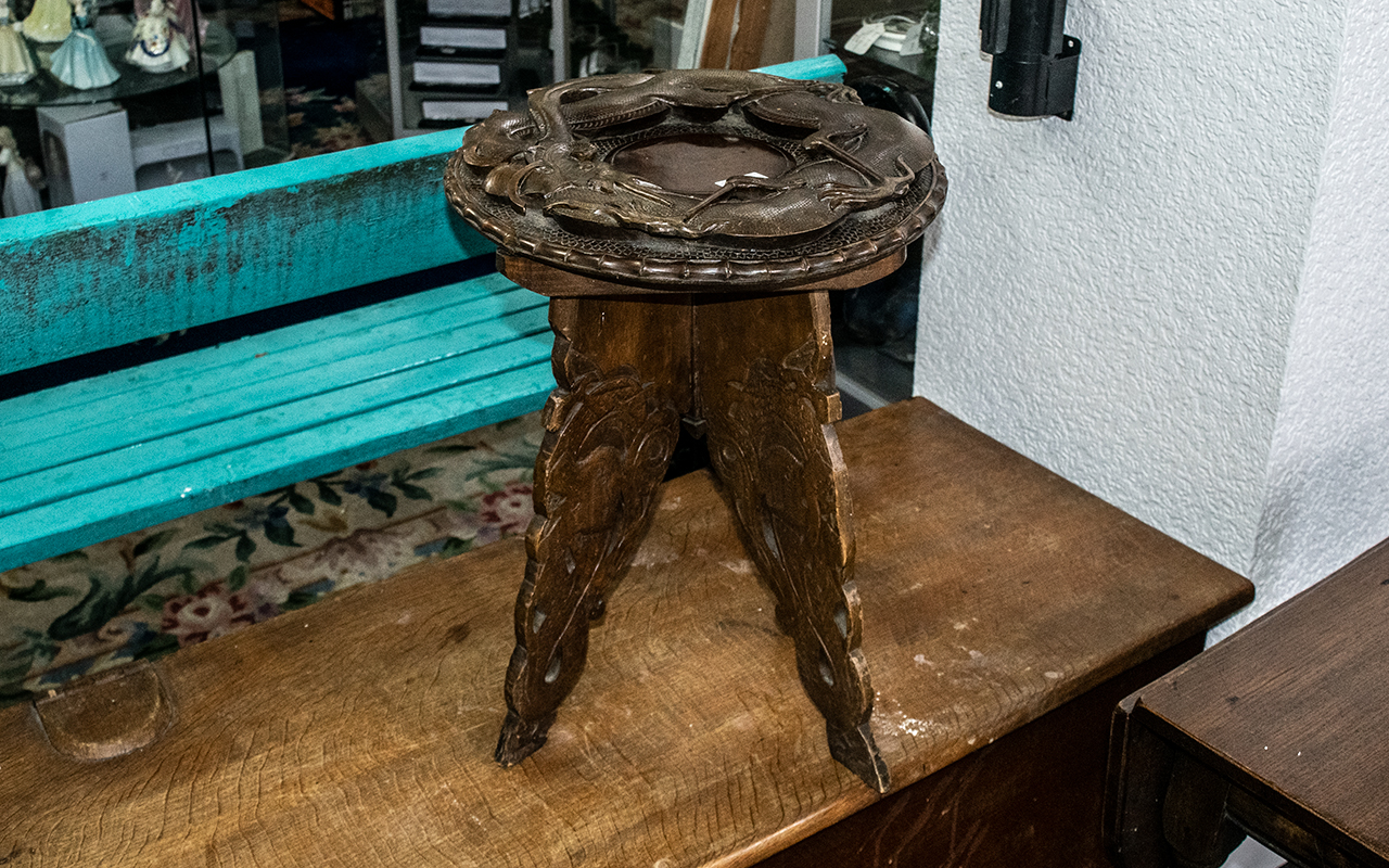 An Indian Carved Wooden Table, the top with raised stylised dragons, on four carved legs. Height