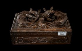 An Oriental Carved Cigar Box, the hinged lid surmounted by mythical beasts,