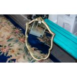 Shield Shaped Mirror, framed in cream a gilt decorated frame. measures 27" x 20.5".