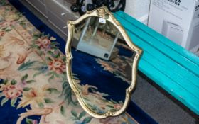 Shield Shaped Mirror, framed in cream a gilt decorated frame. measures 27" x 20.5".