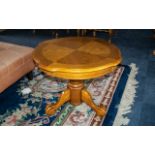 Round Polished Oak Coffee Table, raised on a central pedestal with three splayed legs and claw feet.