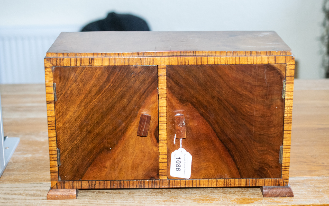 A Wooden Smoker's Cabinet, with double doors, raised on four square feet, fitted with a pipe rack to