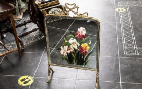 A Brass and Painted Mirror Fire Screen with floral decoration. Height 30 inches, 18 1/2 inches wide.