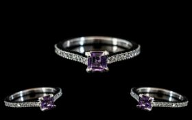 A Platinum Diamond Dress Ring set with a central amethyst coloured stone between shoulders of round