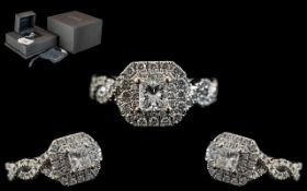 An 18ct White Gold Diamond Ring, set with a central Princess cut diamond, surrounded by round