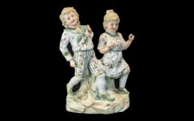 A German Bisque Piano Doll, two children on a rock base, heuback impressed mark.