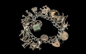 A Silver Charm Bracelet with padlock fastener, loaded with 20+ charms. Gross weight 85 grams.