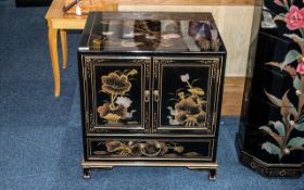 A Chinoiserie Decorated black lacquered cabinet with gilt highlights and landscape decoration.