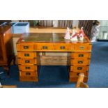 Campaign Style Pedestal Desk, with green leather tooled top, central drawer with five drawers either