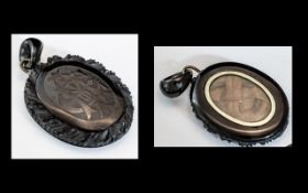 A Victorian Jet Mourning Pendant Carved Front with Glazed Hair Compartment to Reverse.