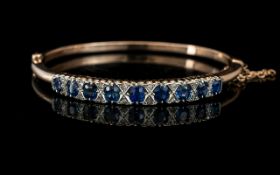 Antique Period 9ct Rose Gold Hinged Bangle Set with Cornflower Blue Sapphires with Diamond Spacers.