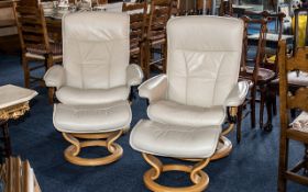 Pair of Cream Leather Stressless Chairs, with matching foot stools, on light wood circular bases.