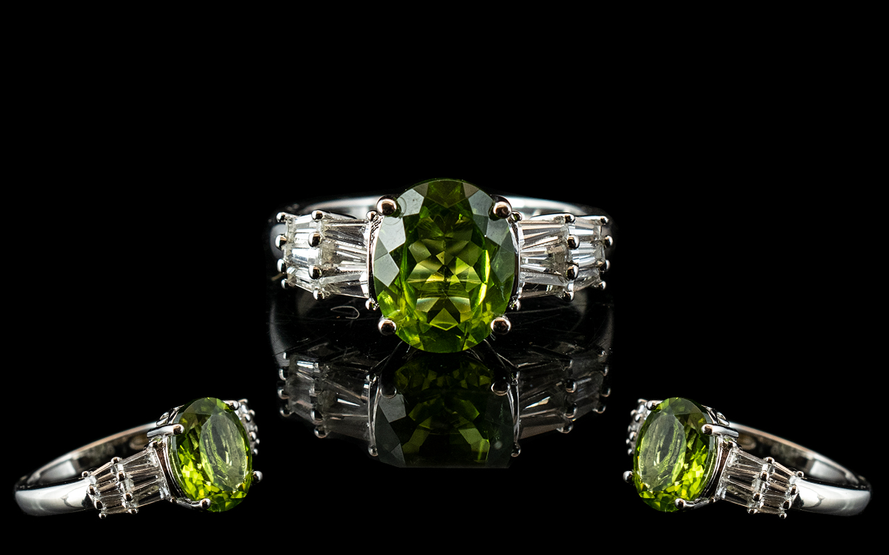 Peridot and Topaz Ballerina Type Ring, a 2.5ct oval cut peridot flanked by two rows of tapered