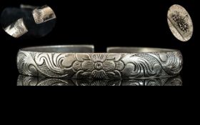 Antique Period Chinese Solid Silver Bangle Decorated With A Central Flower Design On A Hand