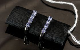 Tanzanite Hinged J-Hoop Earrings, each having four oval cut, bright blue tanzanites, closely set,