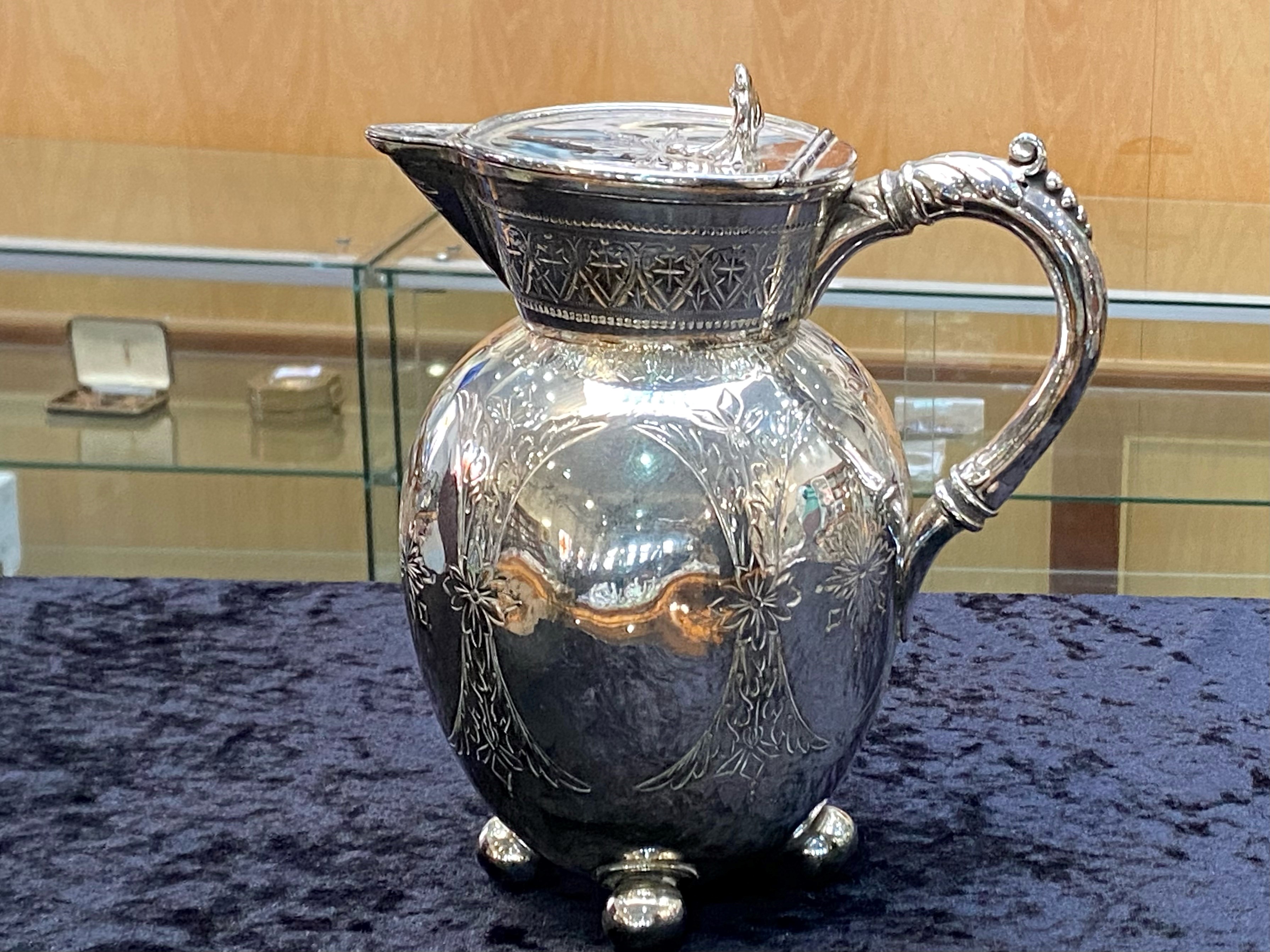 A Victorian Silver Plated Water Jug, raised on cannonball feet, with etched decorations. Height