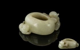 A Brush Pot in White Jade depicting a boy climbing on side. Measures 2 inches wide.