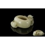 A Brush Pot in White Jade depicting a boy climbing on side. Measures 2 inches wide.