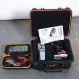 A box of car accessories including a emergency starter kit and a Optimate smart charger kit.