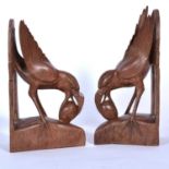 Pair of carved wooden bookends, exotic bird with egg in beak.