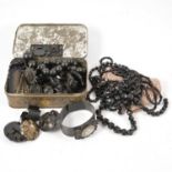 A collection of jet and similar jewellery in a vintage tin.