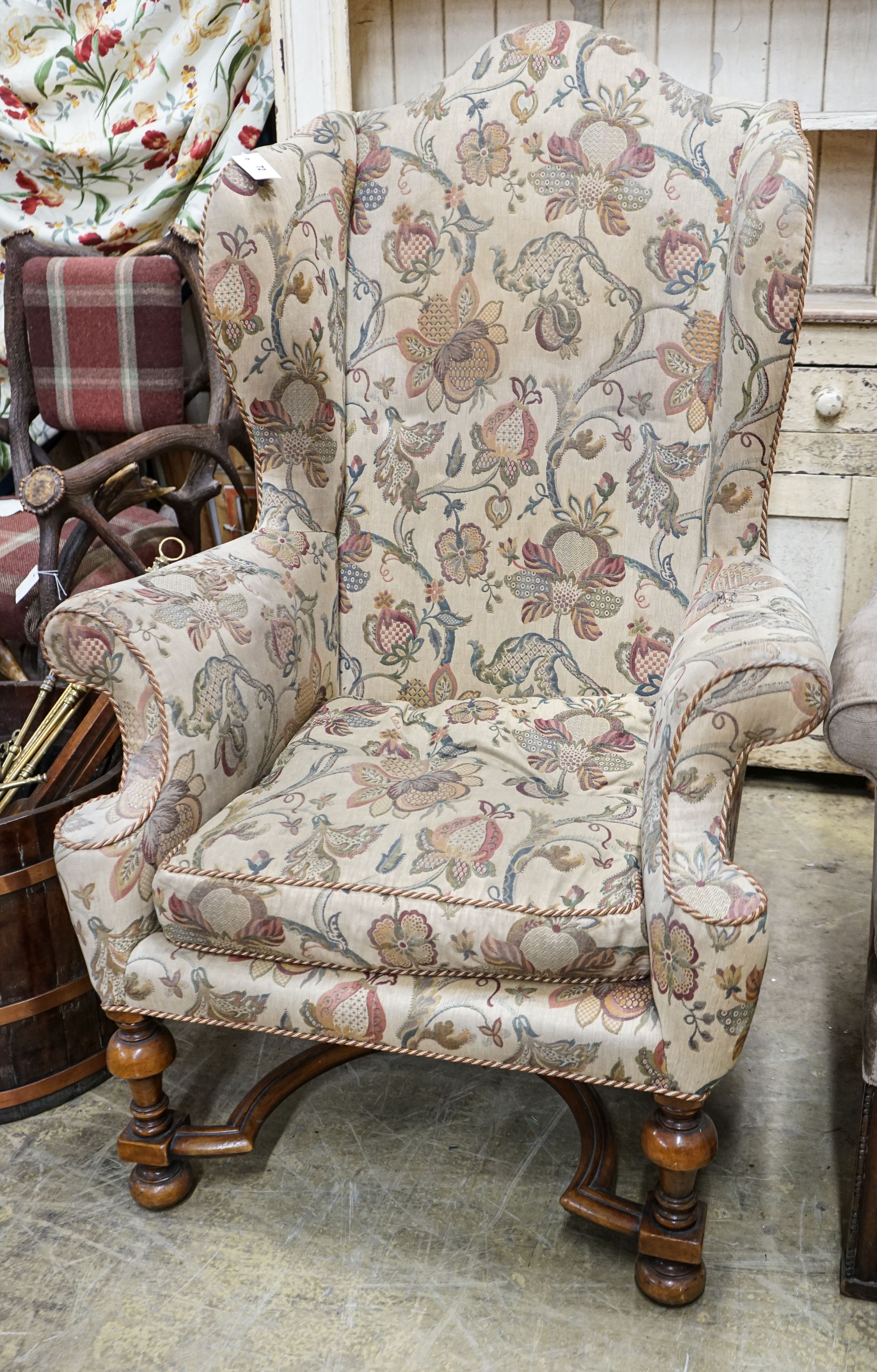 A William & Mary style walnut wing armchair, with flowering scroll upholstery and turned