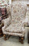 A William & Mary style walnut wing armchair, with flowering scroll upholstery and turned