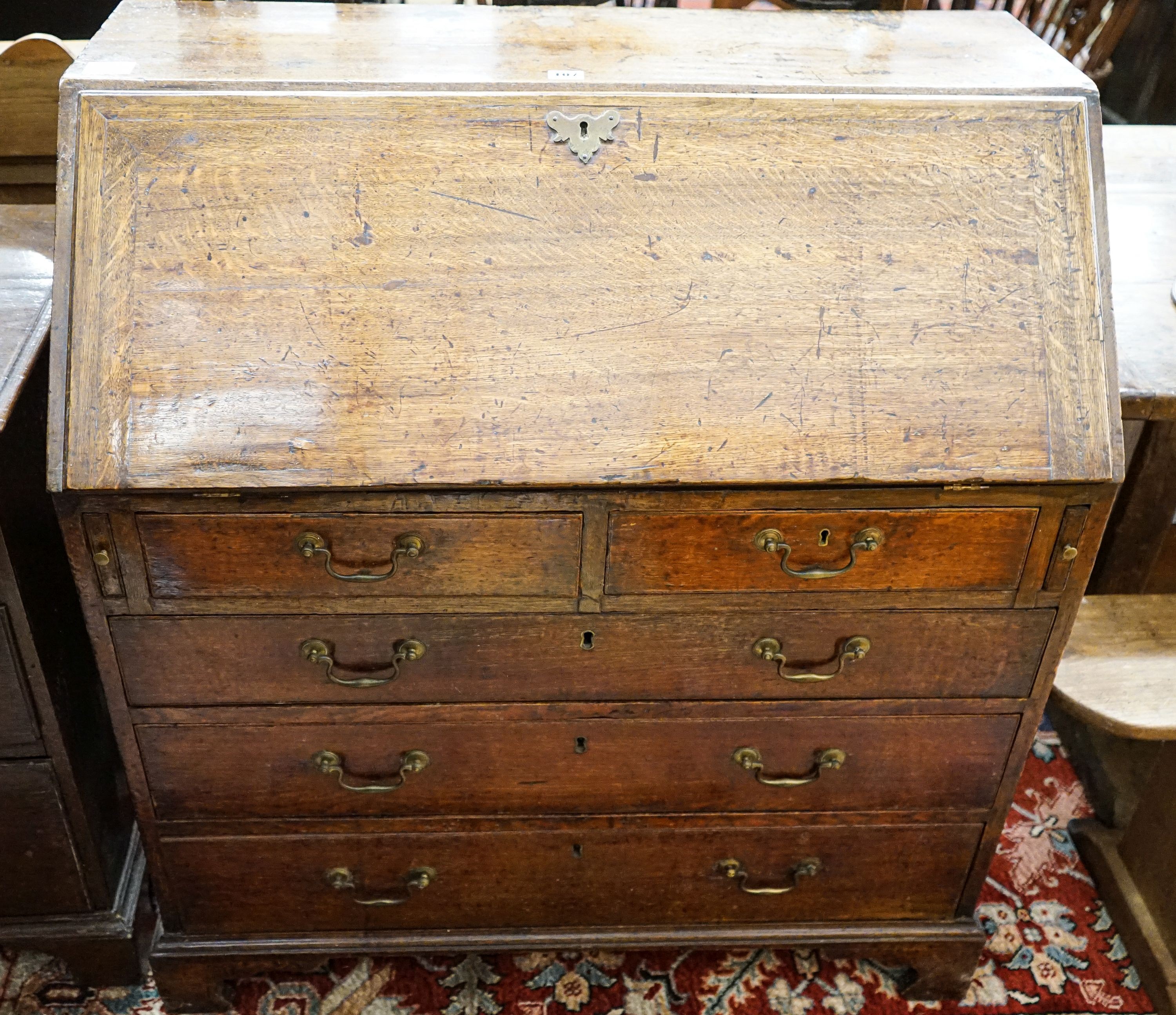 A George III oak bureau, with fitted interior, two short and three long drawers, width 92cm, depth