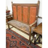 An early 19th century painted pine settle, with four panel back, scroll arms and solid seat, width