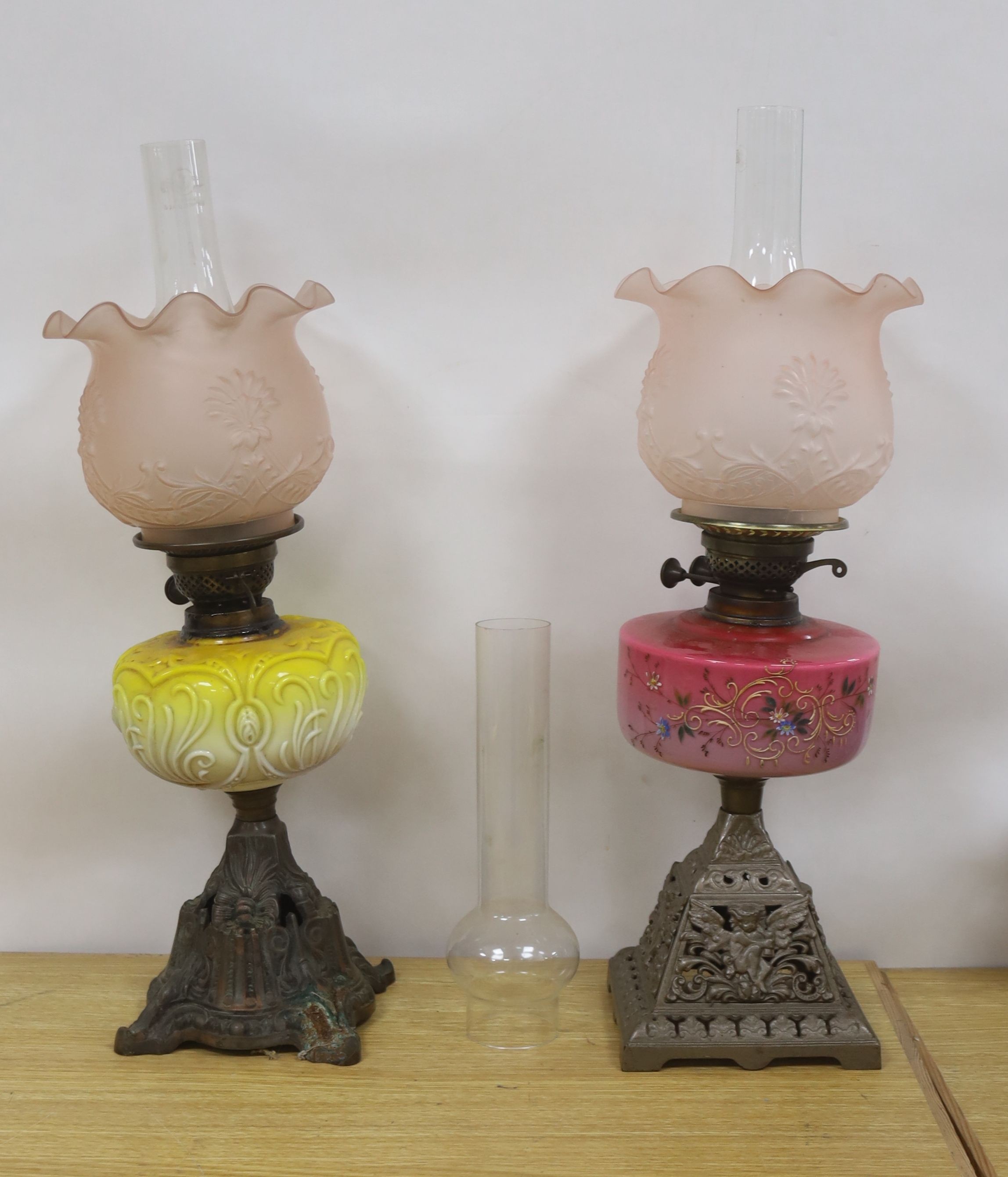 Two late Victorian brass mounted oil lamps with pink and yellow tinted glass reservoirs, tallest