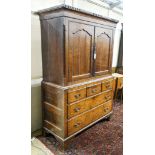 A George III oak press cupboard, with moulded cornice and two panelled doors over five drawers,