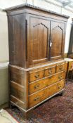 A George III oak press cupboard, with moulded cornice and two panelled doors over five drawers,