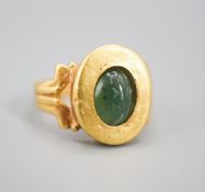 An antique yellow metal and carved nephrite? oval ring, size H, gross 4 grams (the stone is loose in