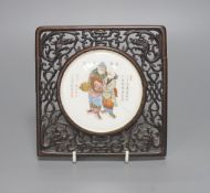 A 19th century Chinese famille rose circular plaque or cover, inset into a wood surround, cracks