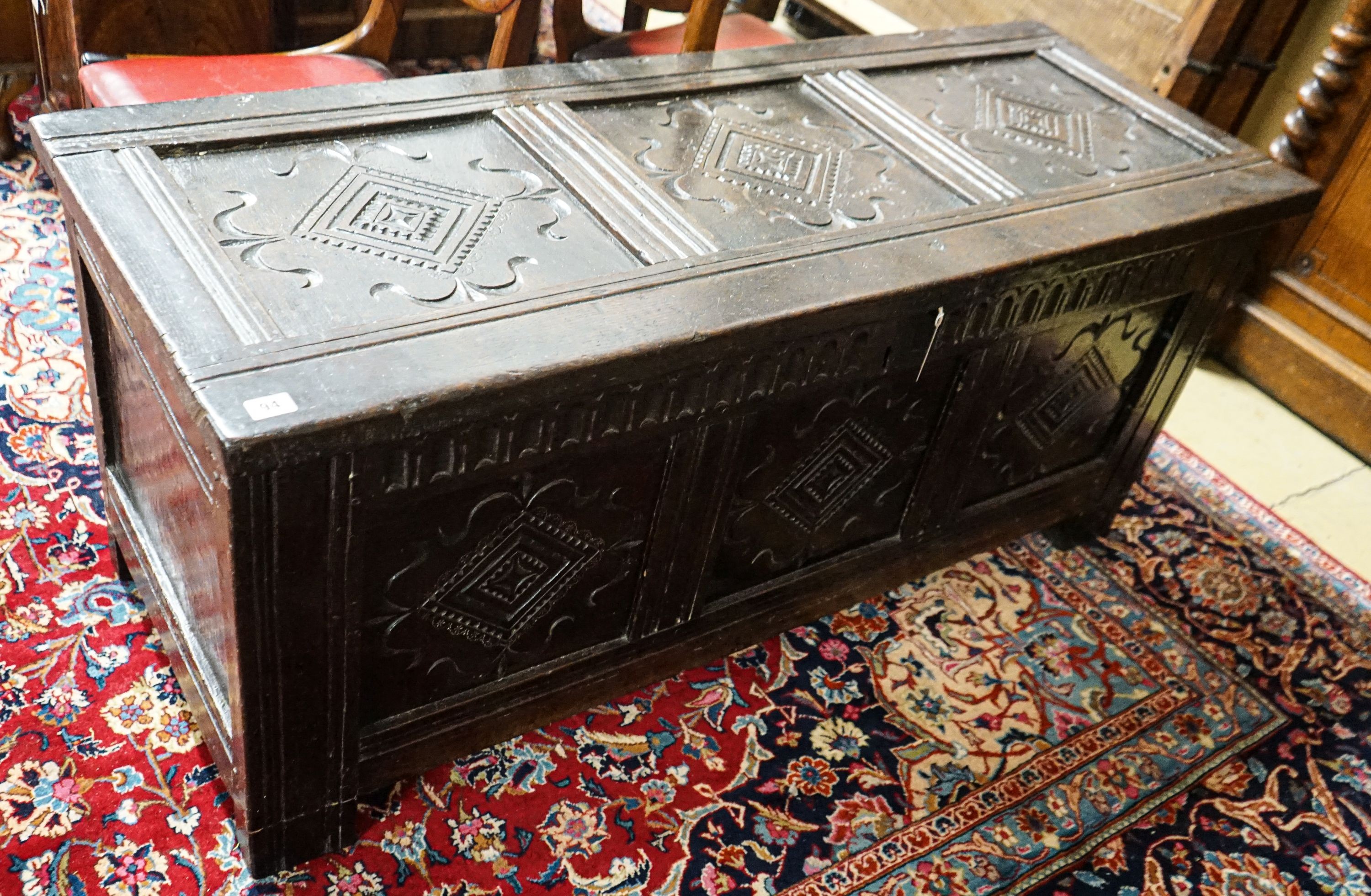 A late 17th/early 18th century carved and panelled oak coffer with hinged lid, width 136cm, depth